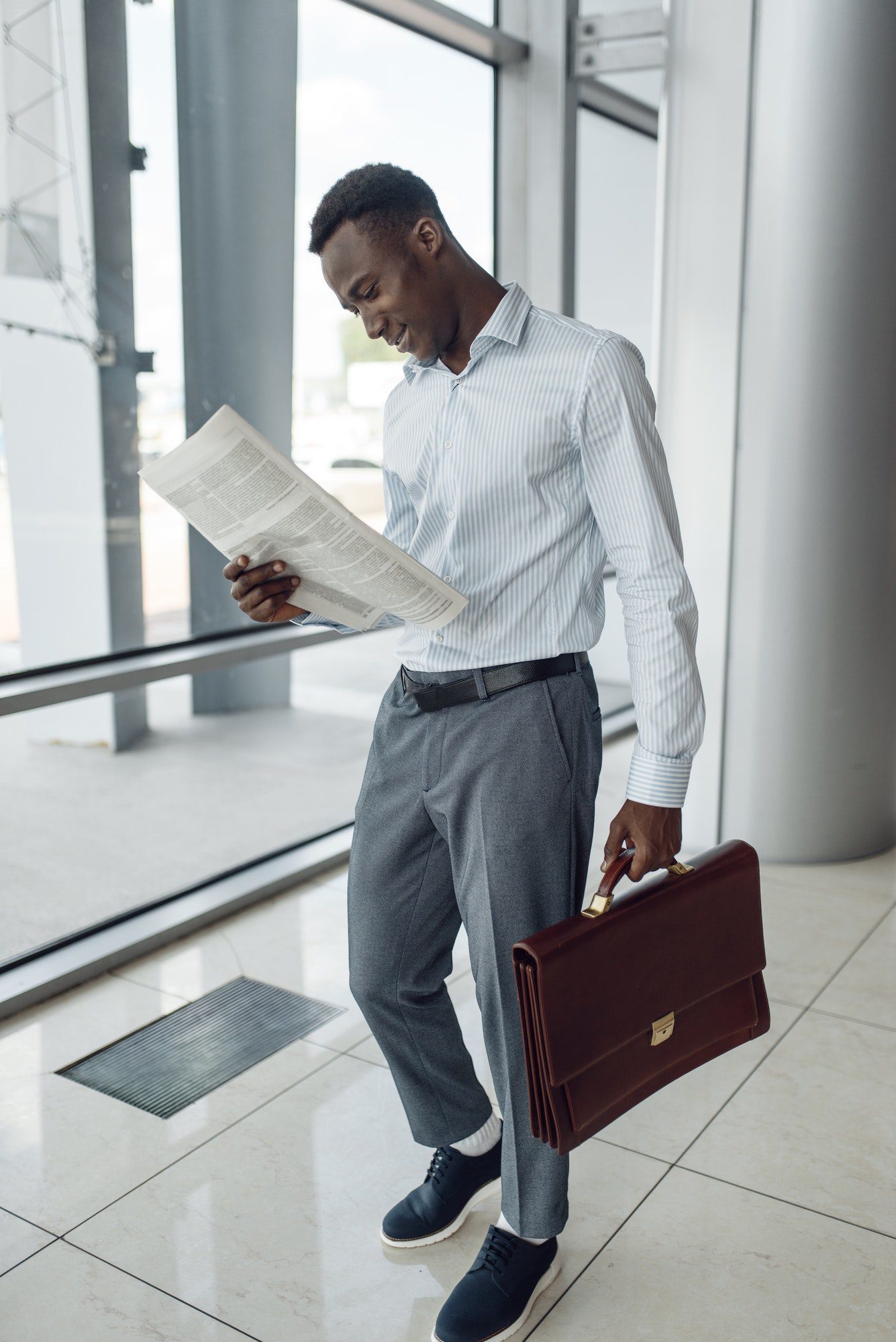 Black businessman with briefcase reading newspaper